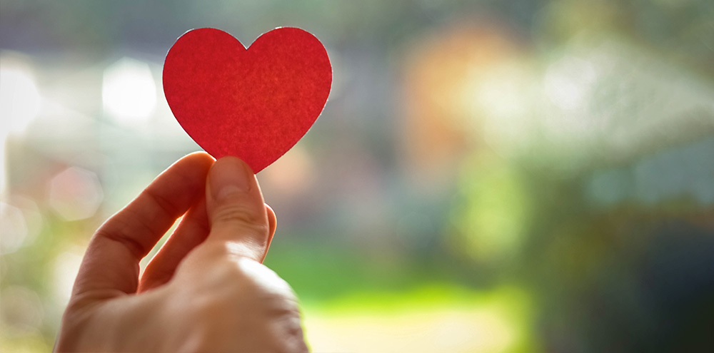 Hand holding red paper heart